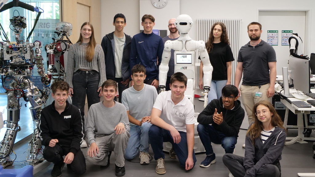 Gruppe von Schülerinnen und Schülern mit Betreuerinnen und Betreuern mit dem Humanoiden Roboter Armar-7