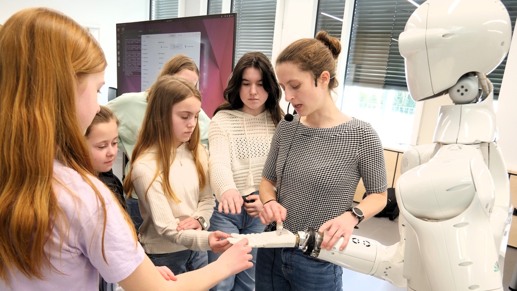 Woman explaining and showing a humanoid robot to a group of girls