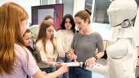 Eine Wissenschaftlerin erklärt umstehenden Schülerinnen die Komponenten des humanoiden Roboters ARMAR-7