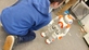 Ein Junge kniet auf dem Boden und sieht den Roboter NAO an